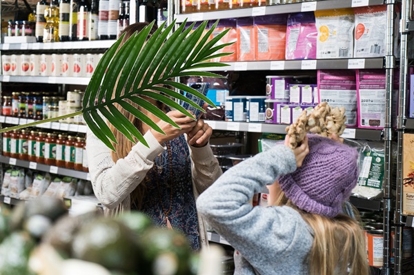 An image of people in a store with a plant obscuring a face.