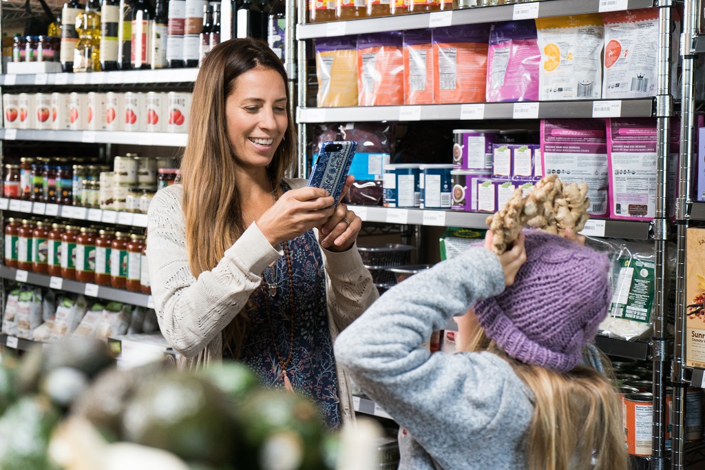 Image of a woman and girl taking a photo with a phone in a grocery store.